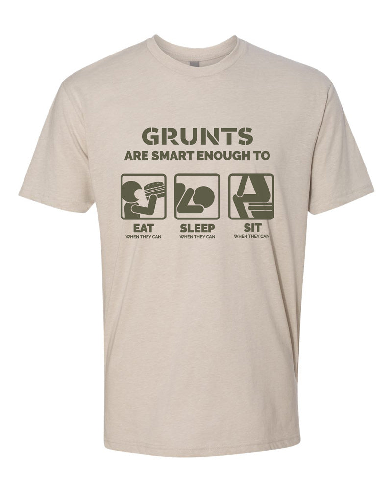 Sand-colored tee with olive text reading "Grunts are smart enough to eat when they can, sleep when they can, sit when they can." Three simplified drawings of a person eating, sleeping, and sitting on a toilet are featured.